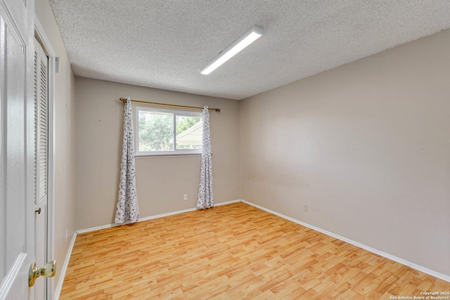 unfurnished room with baseboards, wood finished floors, and a textured ceiling