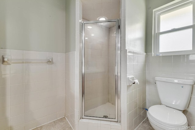 full bathroom featuring tile walls, toilet, a stall shower, and wainscoting