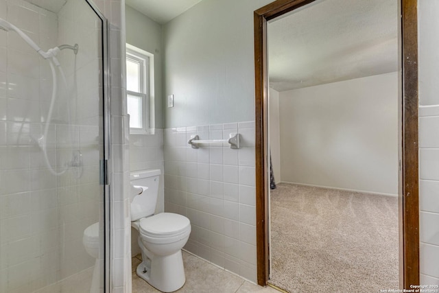 bathroom with a shower stall, tile walls, a wainscoted wall, and toilet