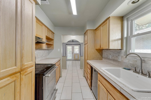 kitchen with arched walkways, a sink, light brown cabinetry, and appliances with stainless steel finishes