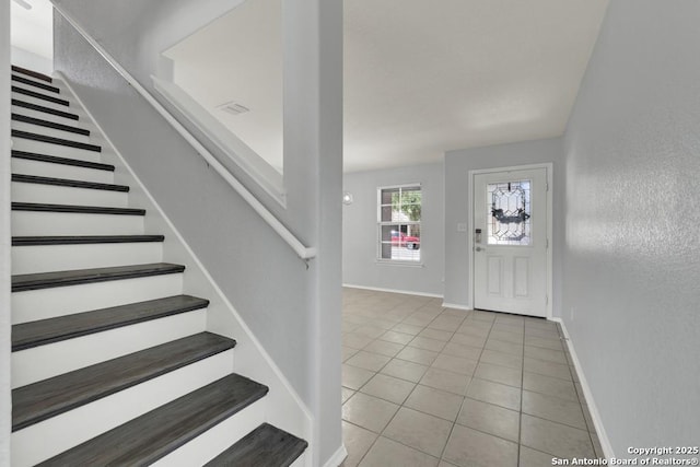 foyer entrance featuring tile patterned floors, baseboards, and stairs