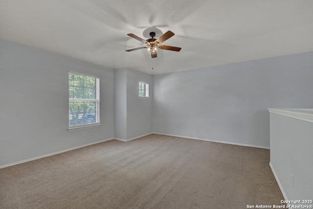 carpeted spare room featuring ceiling fan and baseboards