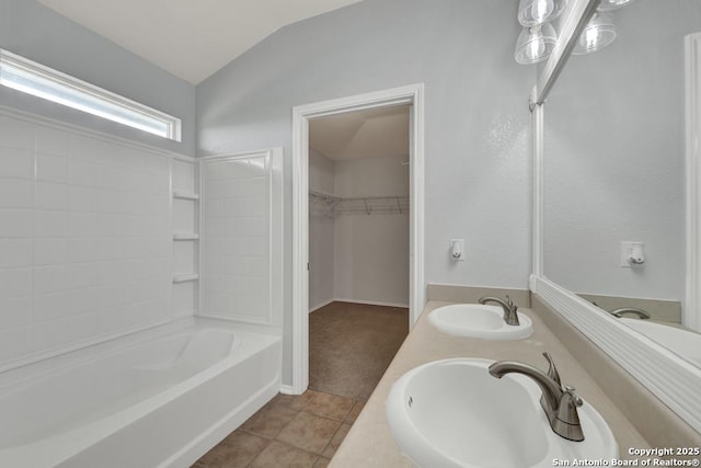 full bath with a spacious closet, tile patterned flooring, a sink, and lofted ceiling