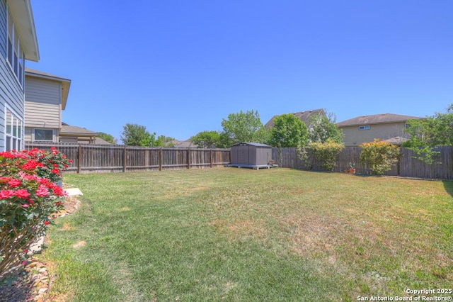 view of yard with a fenced backyard, an outdoor structure, and a storage unit