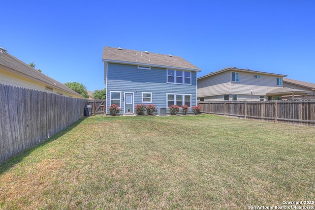 rear view of house with a fenced backyard and a lawn