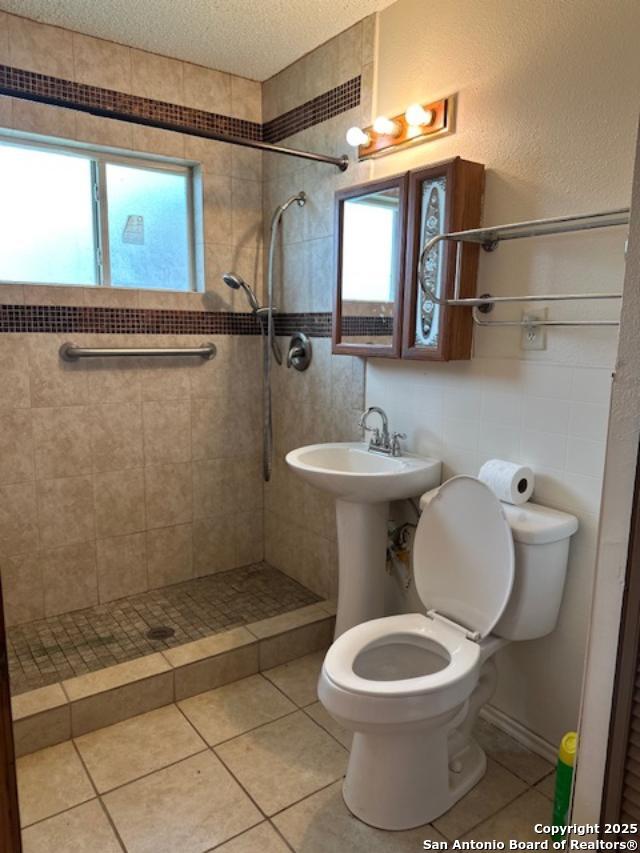 726 Southcross, San Antonio, TX 78211 - bathroom with tile patterned flooring, a tile shower, and toilet