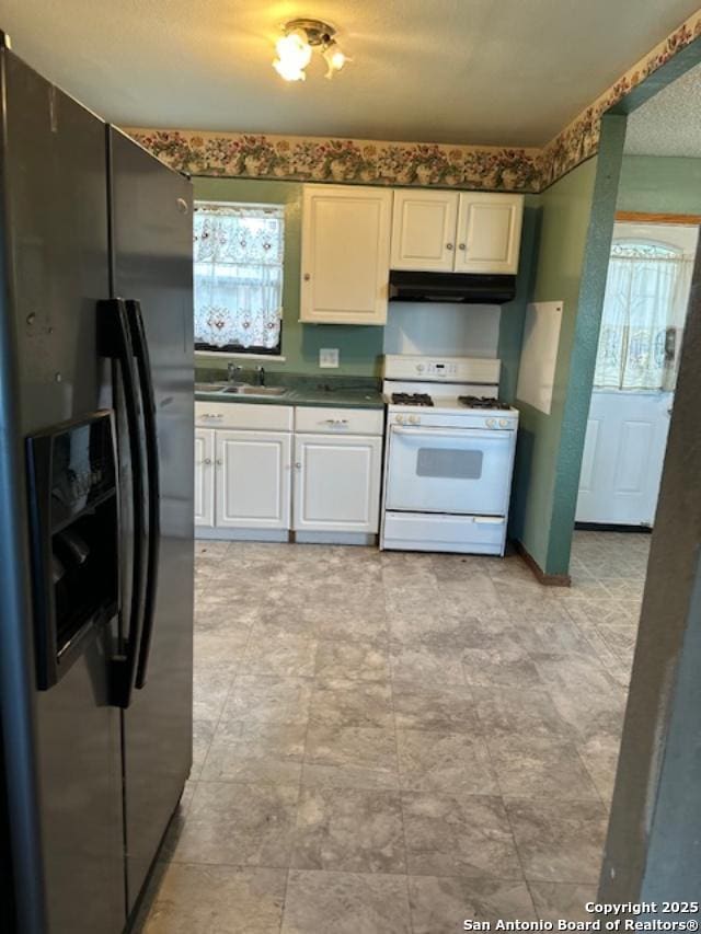 726 Southcross, San Antonio, TX 78211 - kitchen featuring a sink, dark countertops, under cabinet range hood, white gas range oven, and black fridge