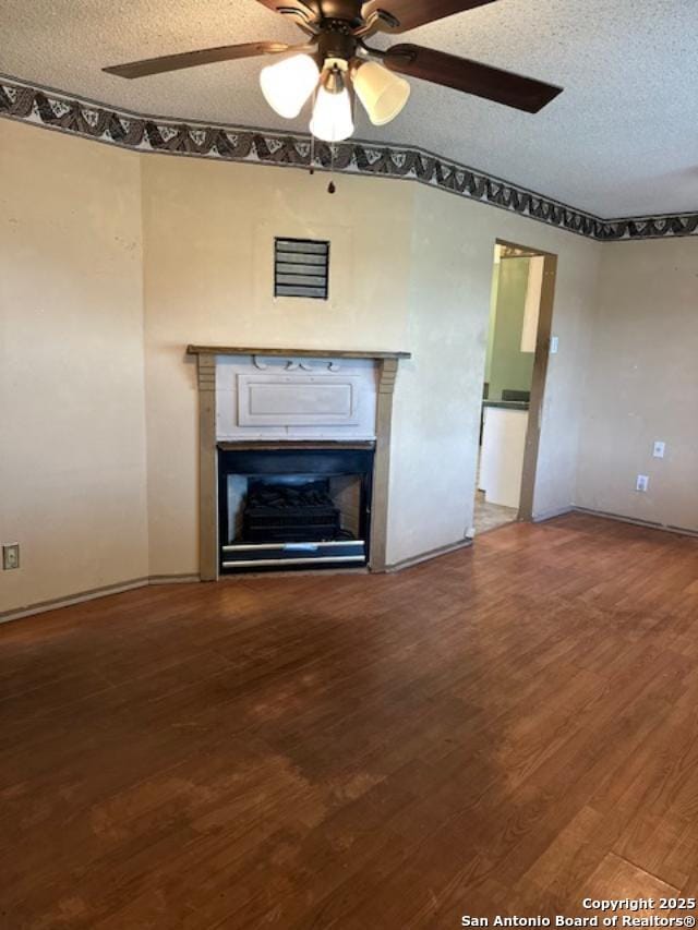 726 Southcross, San Antonio, TX 78211 - unfurnished living room featuring a glass covered fireplace, wood finished floors, baseboards, ceiling fan, and a textured ceiling
