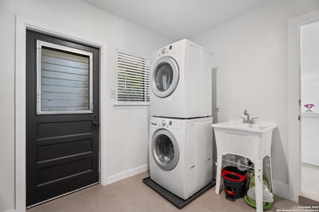 2727 Belvoir, San Antonio, TX 78230 - washroom featuring stacked washer and dryer, light tile patterned floors, baseboards, and laundry area