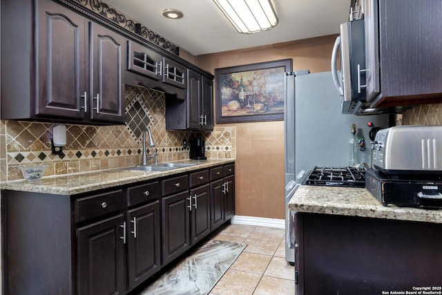 kitchen featuring stainless steel microwave, tasteful backsplash, light tile patterned floors, and a sink