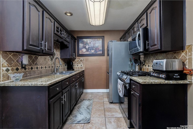 kitchen with backsplash, appliances with stainless steel finishes, a sink, baseboards, and a toaster