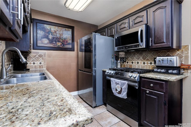 kitchen featuring light countertops, dark brown cabinets, decorative backsplash, stainless steel appliances, and a sink