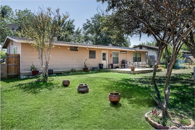 rear view of property with a yard, a patio, and fence