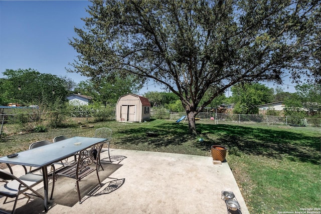 view of patio / terrace featuring an outbuilding, a fenced backyard, outdoor dining area, and a shed