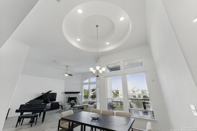 1105 Limestone, New Braunfels, TX 78132 - dining area featuring a raised ceiling, light wood-style floors, a fireplace, recessed lighting, and ceiling fan with notable chandelier