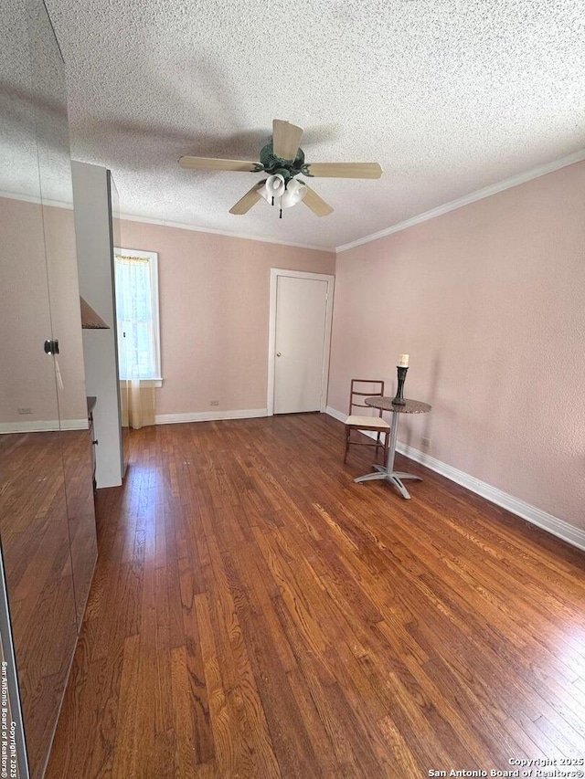 empty room with baseboards, a textured ceiling, crown molding, hardwood / wood-style floors, and ceiling fan