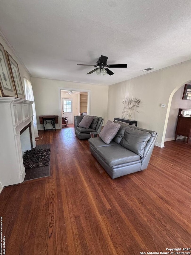 living area featuring baseboards, a ceiling fan, visible vents, arched walkways, and wood finished floors