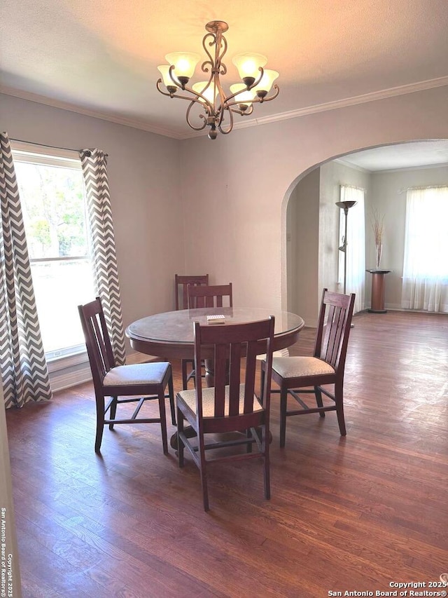 dining space with a chandelier, arched walkways, dark wood-type flooring, and a wealth of natural light