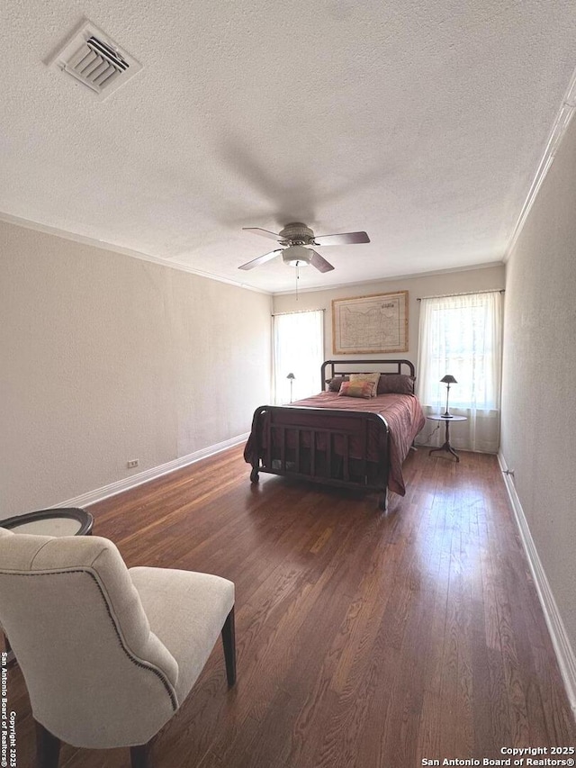 bedroom featuring visible vents, multiple windows, a textured ceiling, and wood finished floors