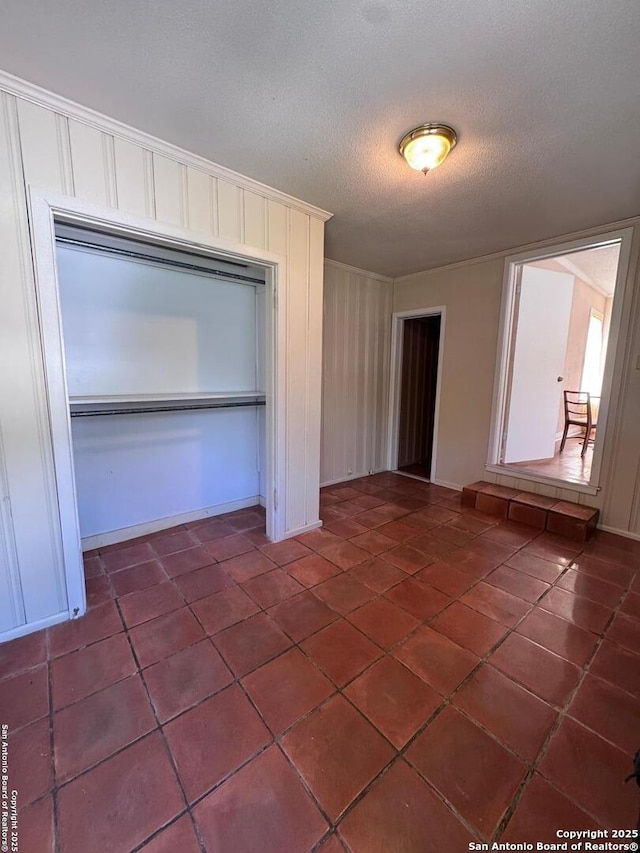 unfurnished bedroom with a closet, dark tile patterned floors, a textured ceiling, and ornamental molding