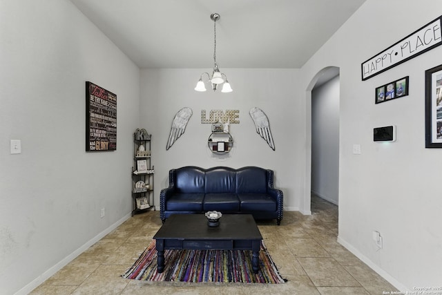 living room featuring baseboards, arched walkways, a notable chandelier, and light tile patterned flooring