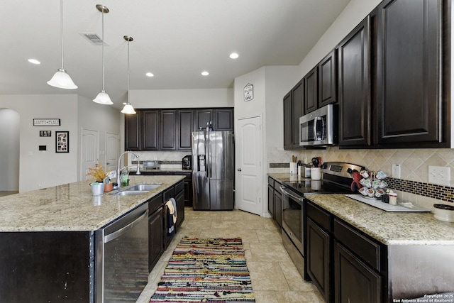 kitchen with tasteful backsplash, light stone counters, visible vents, appliances with stainless steel finishes, and a sink