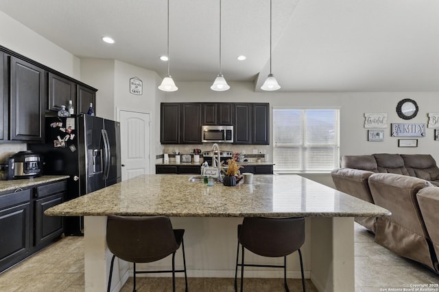 kitchen featuring open floor plan, a breakfast bar area, appliances with stainless steel finishes, and a sink