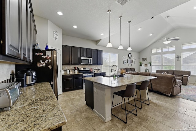 kitchen with a kitchen bar, a ceiling fan, a sink, stainless steel appliances, and decorative backsplash