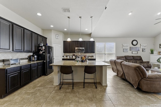 kitchen with open floor plan, visible vents, stainless steel microwave, and black fridge with ice dispenser