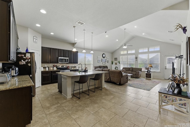 kitchen featuring visible vents, appliances with stainless steel finishes, a sink, open floor plan, and a center island with sink