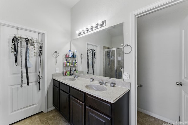 full bathroom with double vanity, baseboards, a sink, and a stall shower