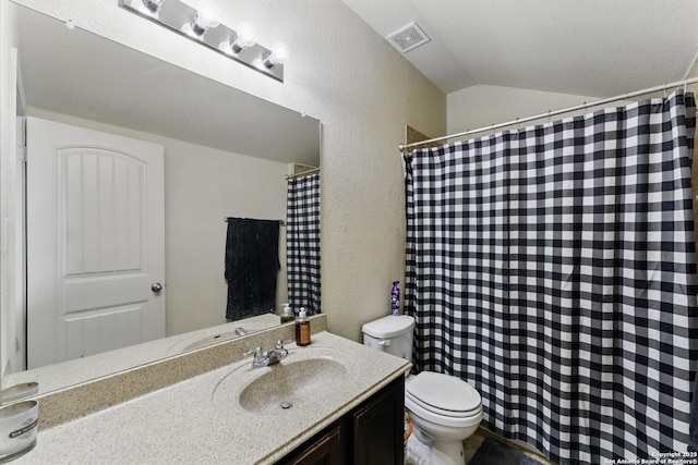 full bath with vanity, a textured wall, toilet, visible vents, and lofted ceiling