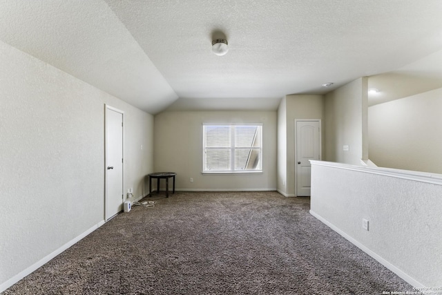 carpeted empty room with baseboards, a textured ceiling, a textured wall, and lofted ceiling