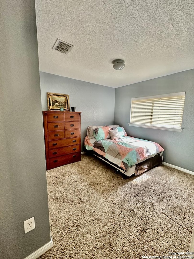 bedroom with a textured wall, visible vents, a textured ceiling, and carpet floors