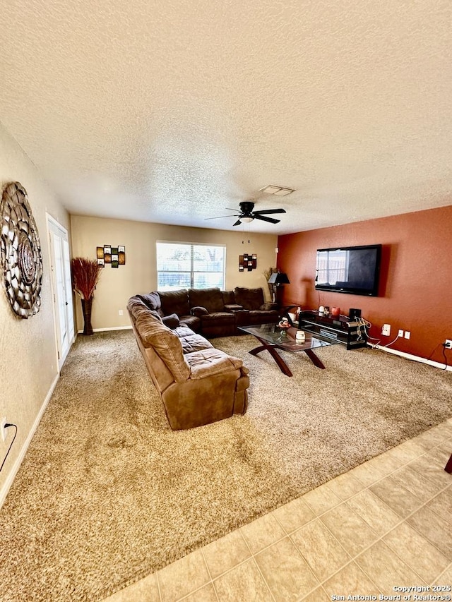 carpeted living area featuring baseboards, tile patterned flooring, a textured ceiling, a ceiling fan, and visible vents