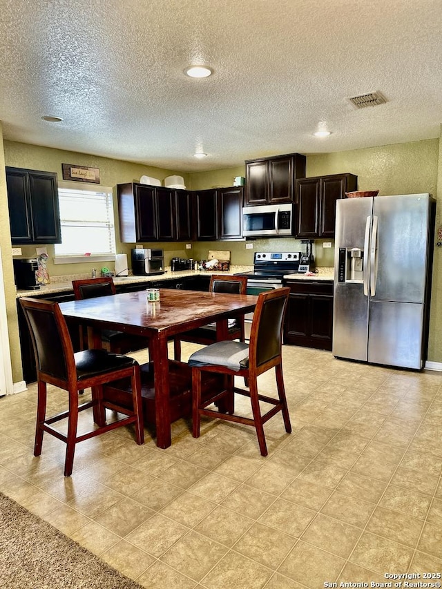 kitchen featuring a textured ceiling, light countertops, visible vents, and stainless steel appliances