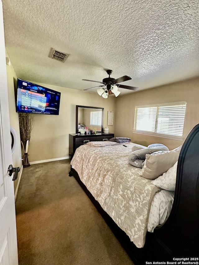 carpeted bedroom with visible vents, ceiling fan, baseboards, and a textured ceiling