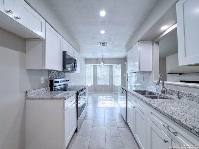 kitchen with tasteful backsplash, visible vents, a sink, appliances with stainless steel finishes, and a textured ceiling