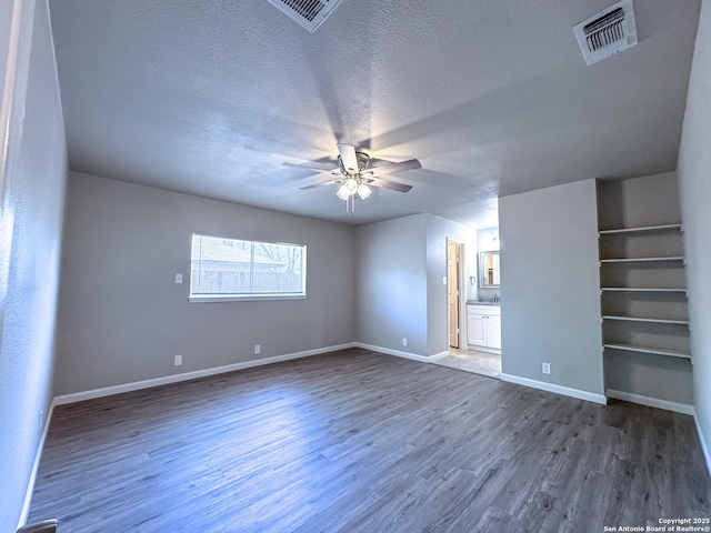 spare room with dark wood-style flooring, visible vents, a ceiling fan, and a textured ceiling