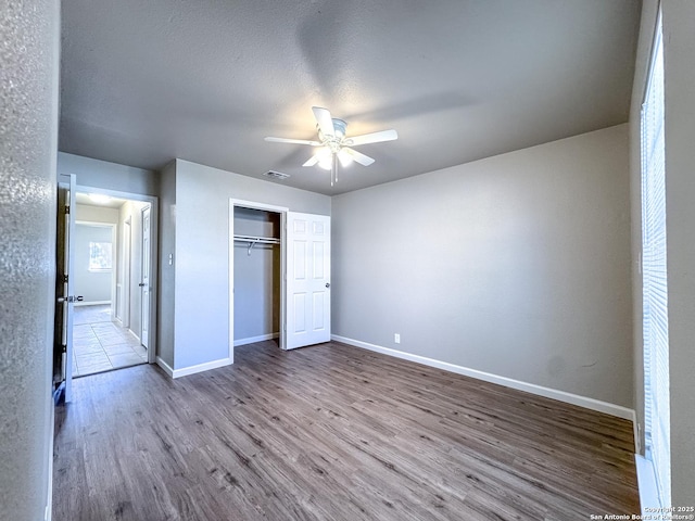 unfurnished bedroom featuring a closet, visible vents, baseboards, and wood finished floors