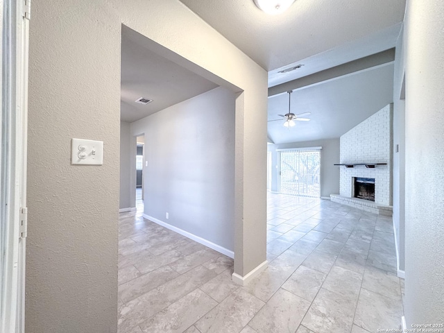 hall featuring visible vents, vaulted ceiling, and a textured wall