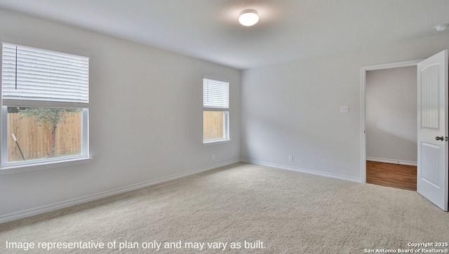 carpeted empty room featuring baseboards