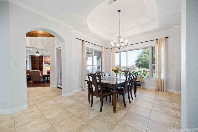 dining room featuring an inviting chandelier, a raised ceiling, arched walkways, and plenty of natural light