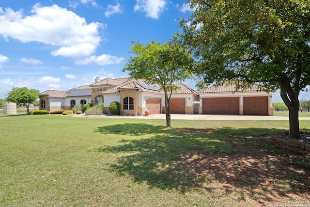 view of front of house with roof mounted solar panels, a front yard, a tile roof, an attached garage, and driveway