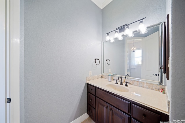 bathroom with ornamental molding, vanity, and a textured wall
