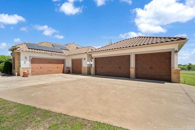 view of front facade featuring concrete driveway, stucco siding, solar panels, a garage, and a tiled roof