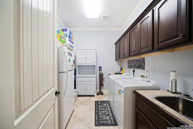 laundry area with crown molding, light tile patterned flooring, a sink, washer and dryer, and cabinet space