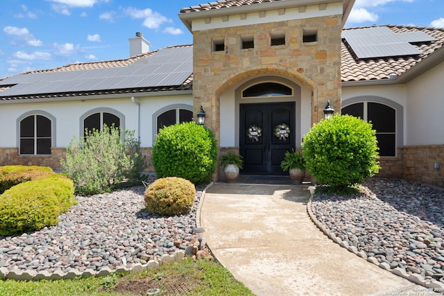 doorway to property featuring french doors, stone siding, a chimney, and stucco siding