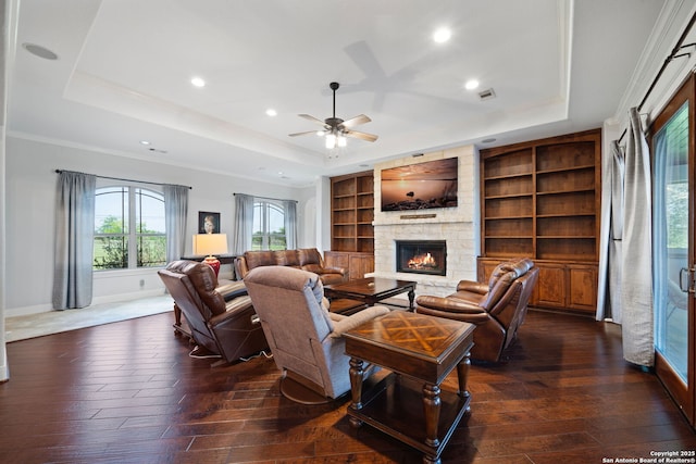 living area with a fireplace, dark wood-style flooring, a tray ceiling, and baseboards