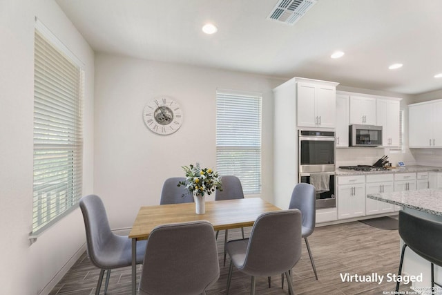 dining area featuring visible vents, light wood-style floors, and a healthy amount of sunlight